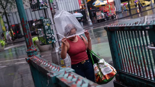 A person with a plastic bag over their head on the stairs of a subway station entrance