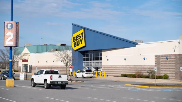 A bright yellow sign against a blue roof says "Best Buy" in bold black letters.