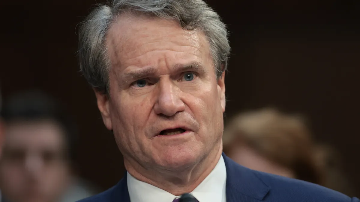 Bank of America CEO Brian Moynihan speaks during a Congressional hearing, with people in the background behind him