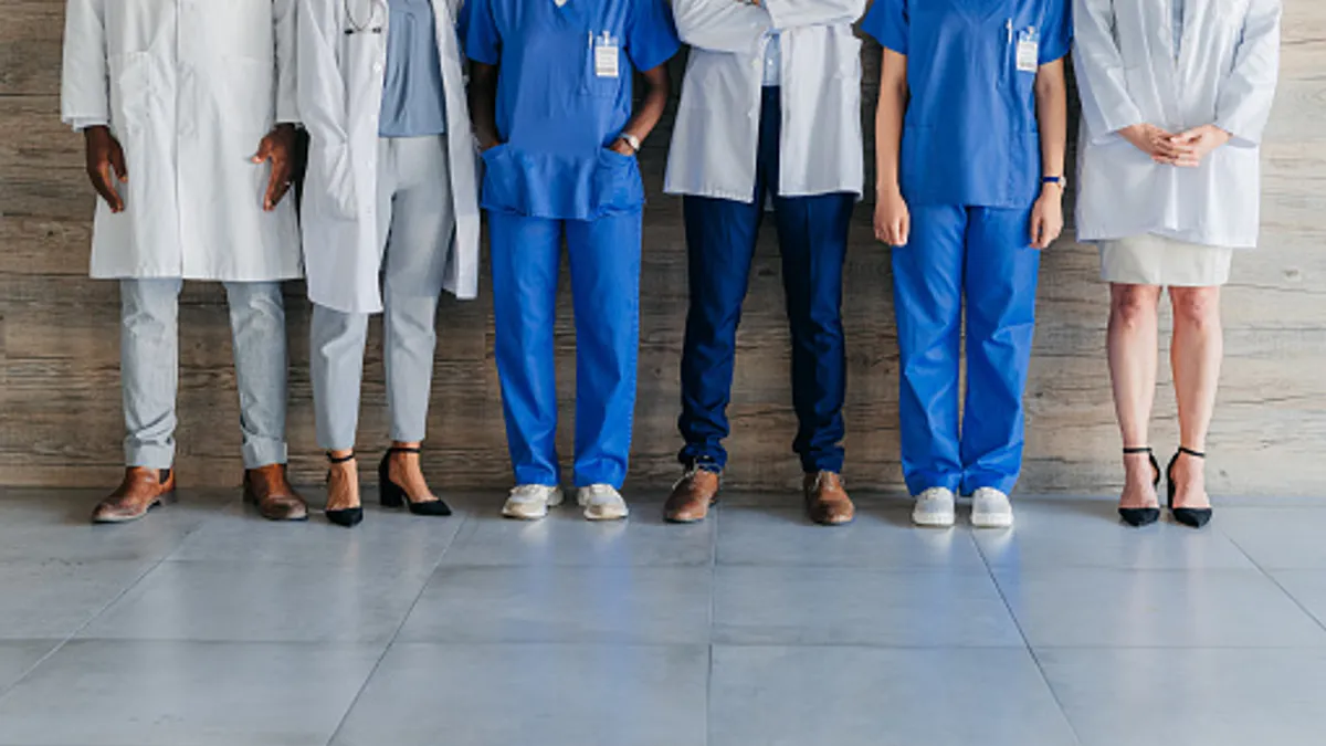 Team of professional, medical coworkers, against wood background, together show diversity, in hospital corridor.