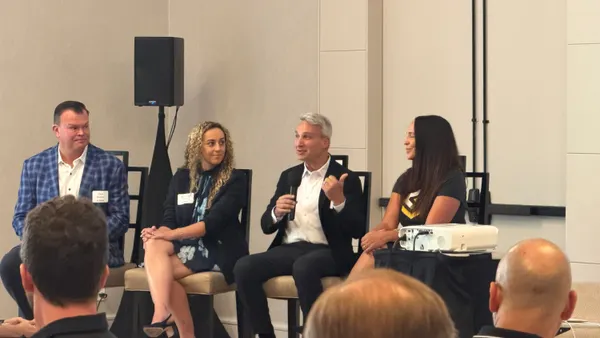 four people sitting in chairs speaking as part of panel