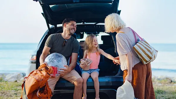 Travelers sit in a car overlooking a body of water.