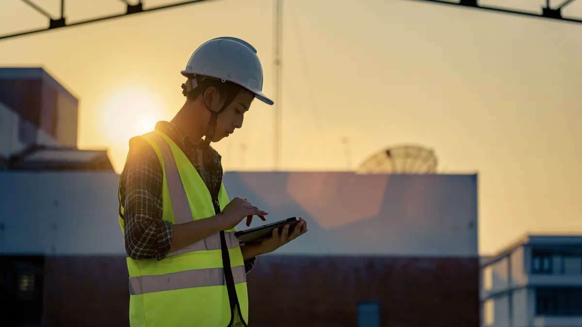 A young construction worker uses a tablet to view plans on a jobsite.