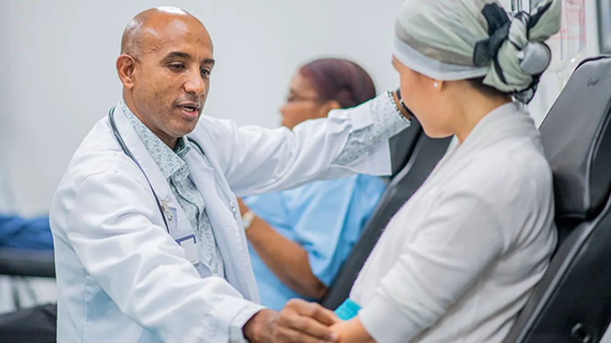 Male Doctor giving intravenous drip chemotherapy treatment to a female cancer patient.