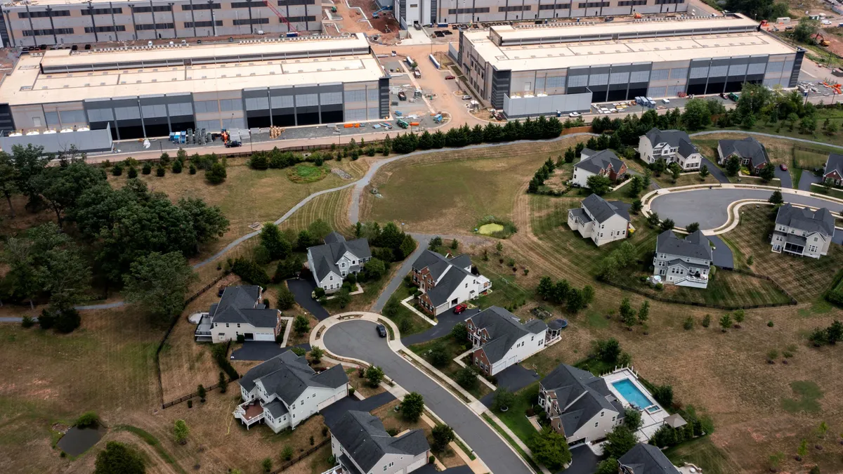 An aerial view of house near large warehouse-like buildings.
