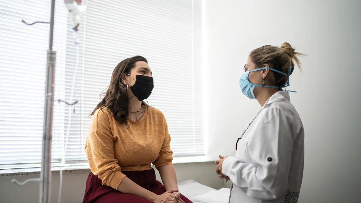 Patient talking to doctor on medical appointment - wearing protective face mask