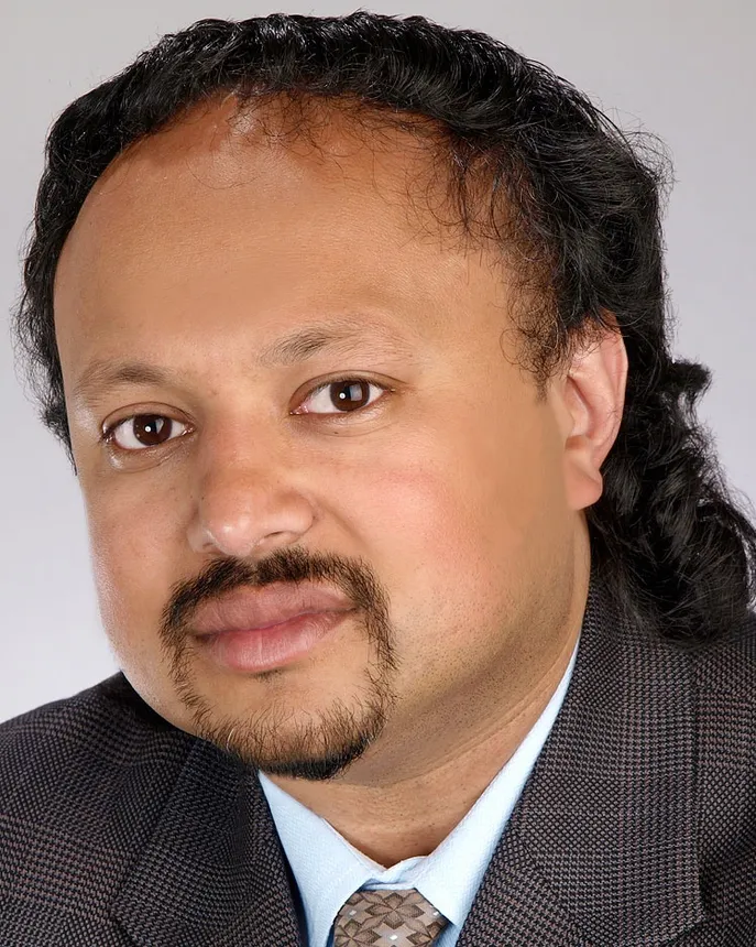 Headshot of a man with black curly hair.