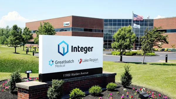 A white sign in front of a brick and glass building says "Integer."