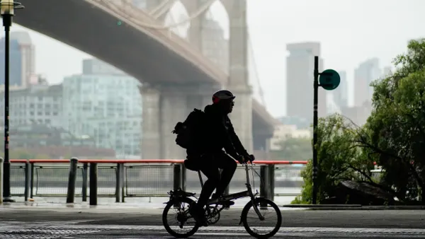 Silhouette of a man riding a bike under the Brooklyn Bridge.