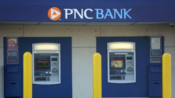 Two blue ATMs are housed within a modern facade featuring the PNC logo above and are accessible from the sidewalk.