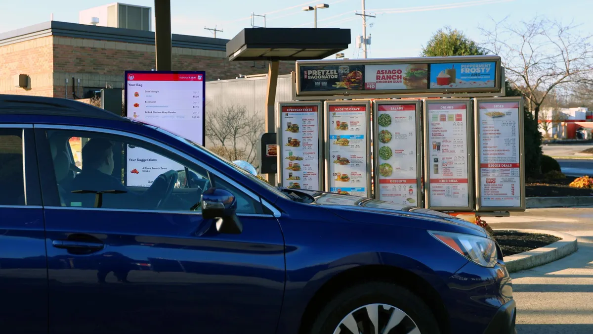 A man in a dark car at a Wendy's drive-thru that uses artificial intelligence to take orders