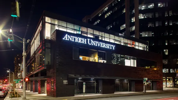 Building at night with illuminated sign and lights from street lamps and traffic.