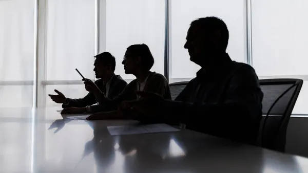 Silhouette of several business people at a conference room table.