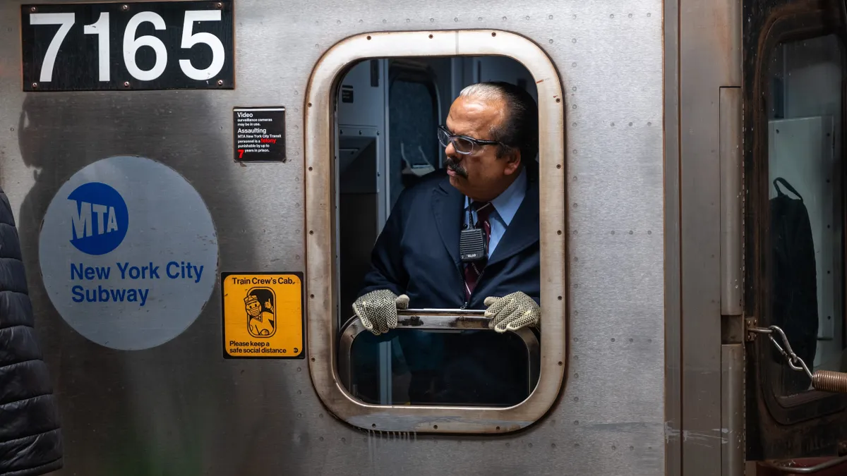 A man in the cab of a subway car looks out the window.