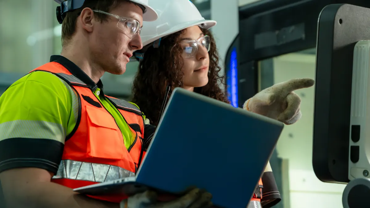 A man and woman discussing wearing construction hats