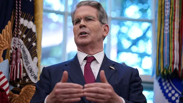 Treasury Secretary Scott Bessent speaks in front of a window while gesturing with his hands