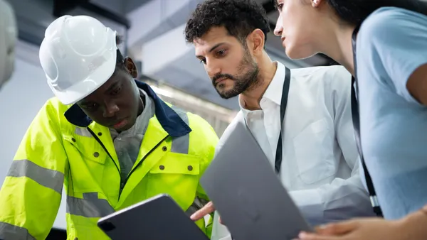 An engineer and building managers look at data on a tablet.