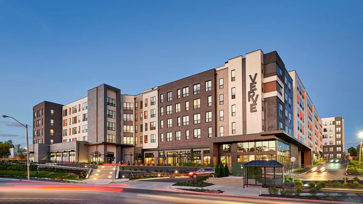 A seven-story mixed-use brown and white apartment building.