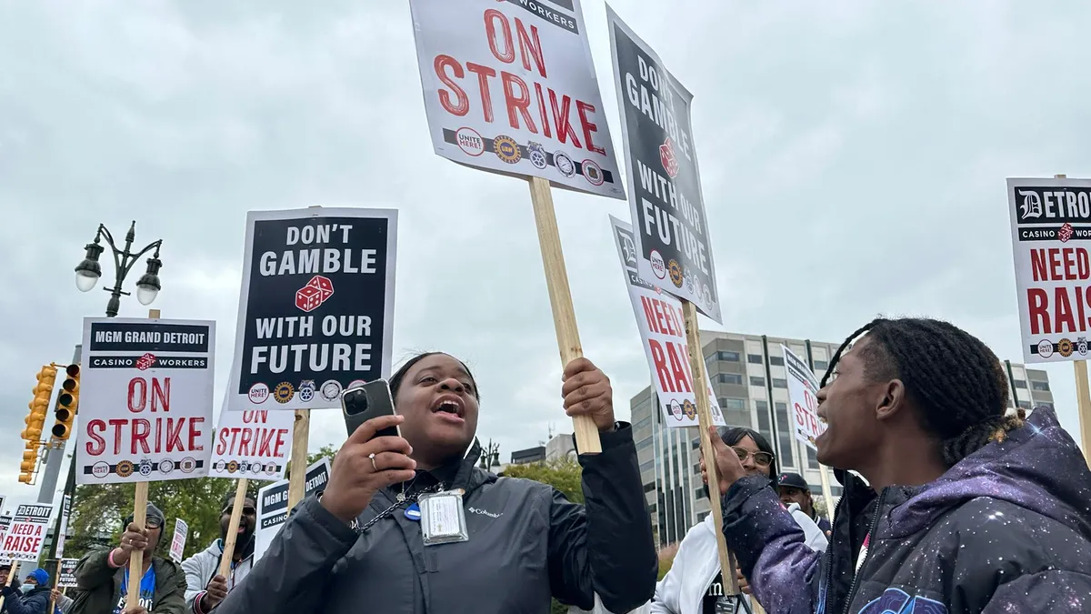 Workers hold picket signs saying 'ON STRIKE.'