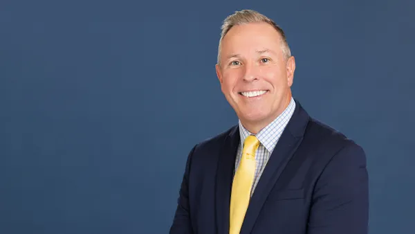 A person in a suit smiles at the camera