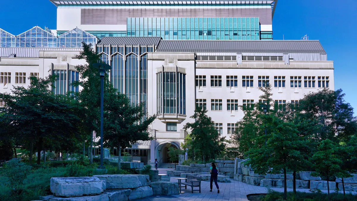 A student walks on the pathway toward a University of Chicago campus building.