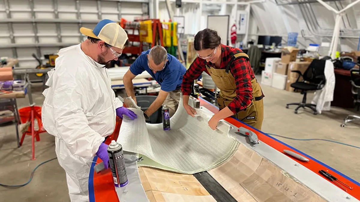 NREL researchers work on a wind turbine blade assembled with their biobased resin.