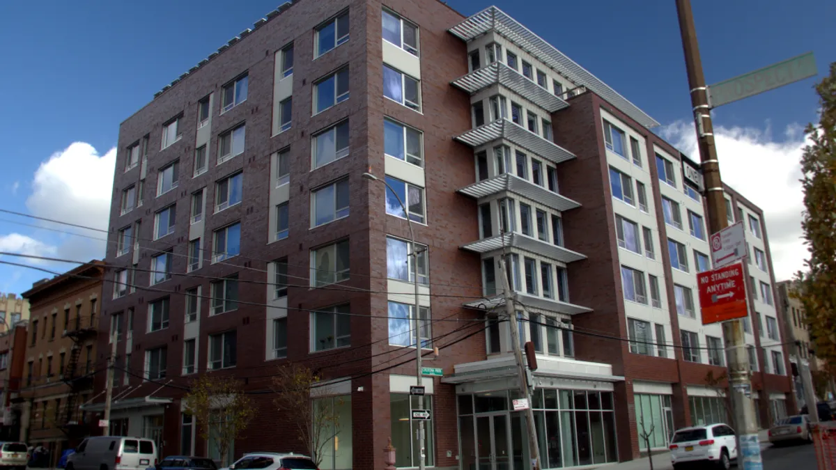 The exterior of a box shaped apartment building on a sunny day.