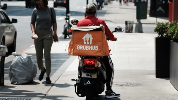 A food delivery worker is shown on a scooter