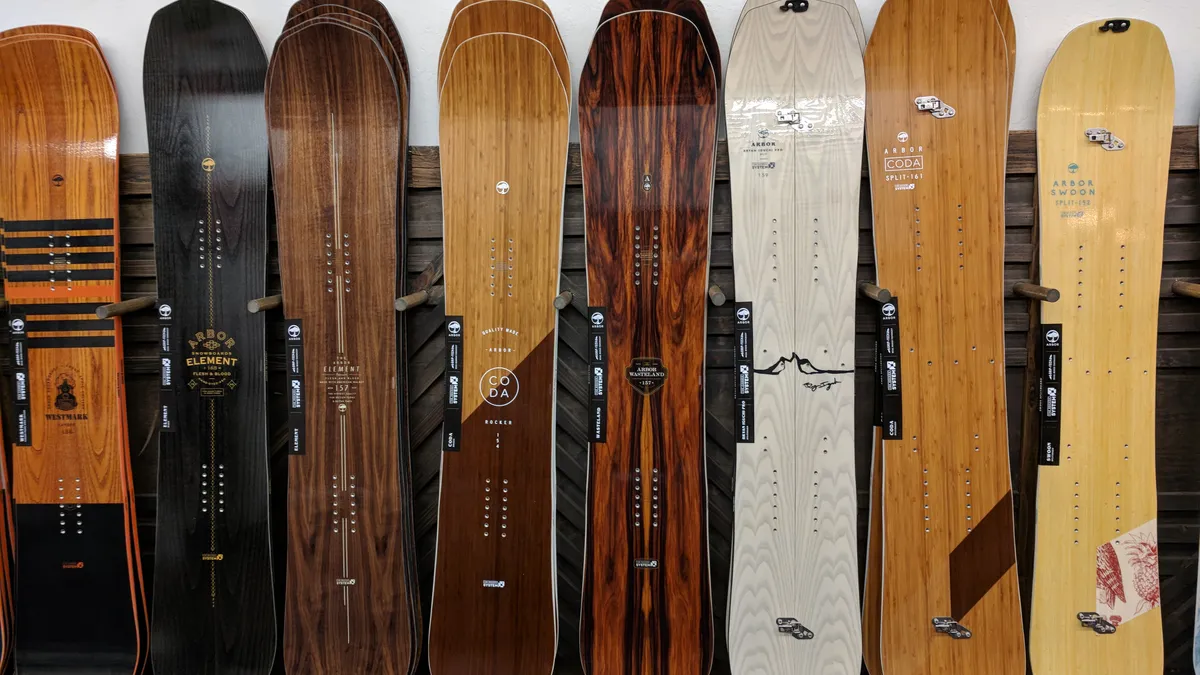 A line of wood snowboards displayed against a wall in a store.