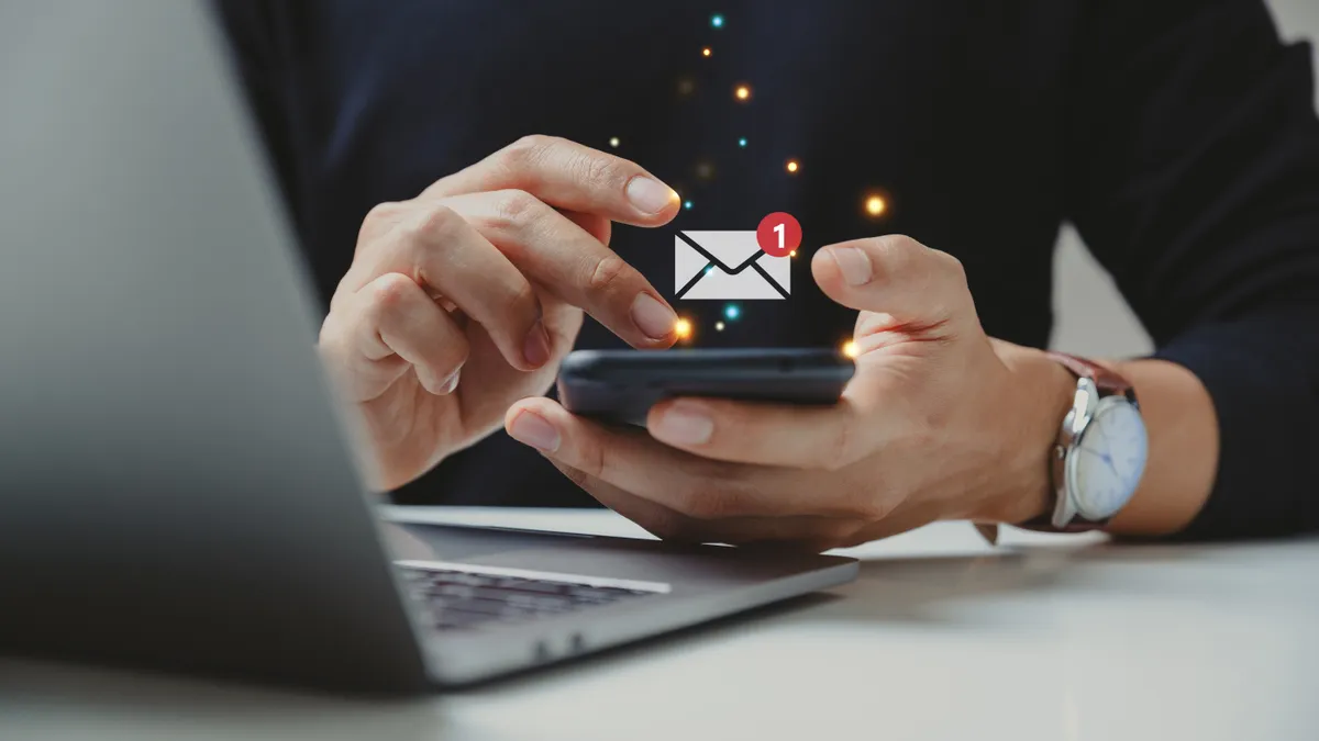 A businessperson holding their smartphone receives an email notification