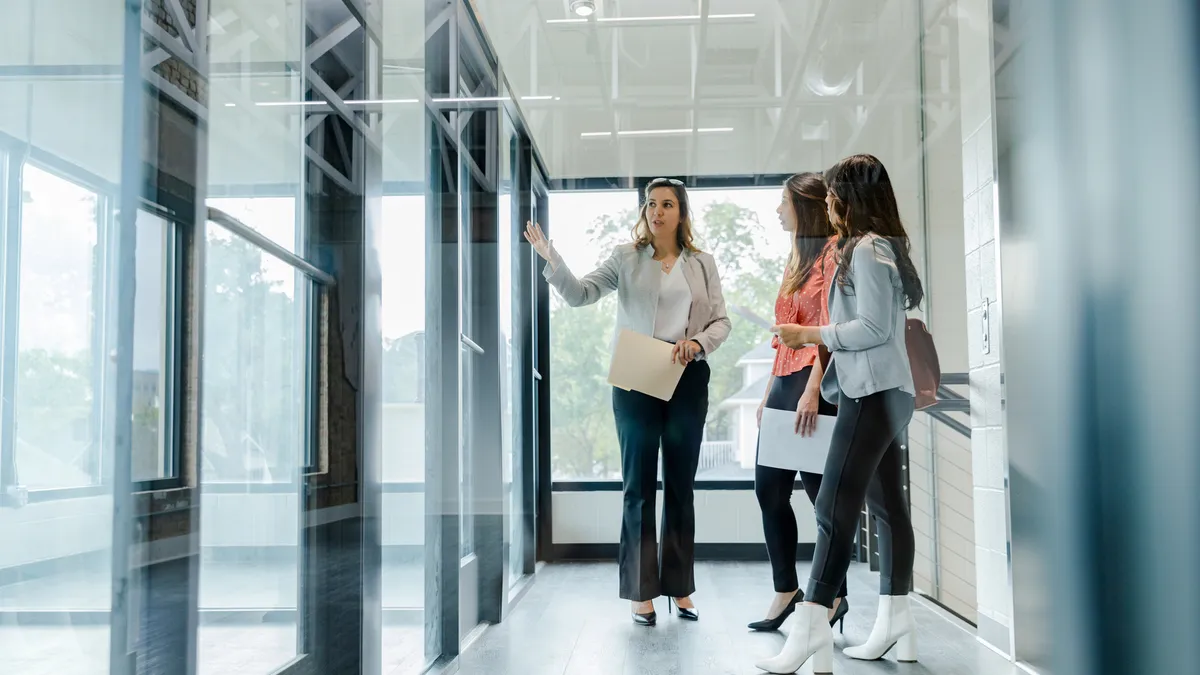 A female real estate agent is seen describing a commercial property to two entrepreneurs.