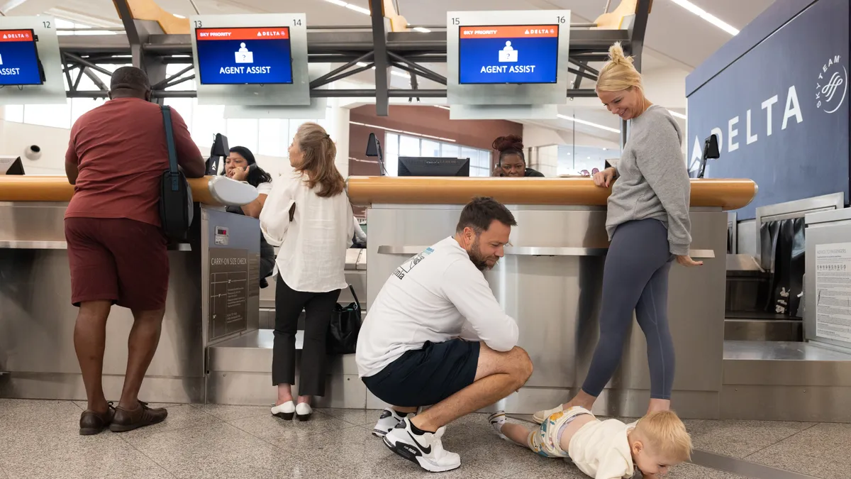 A family stands at a Delta Air Lines ticketing counter trying to rebook a flight after a CrowdStrike software update caused thousands of cancelations.