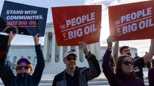 People hold signs that say, "Stand with Communities, Not Big Oil" and "The People v. Big Oil"