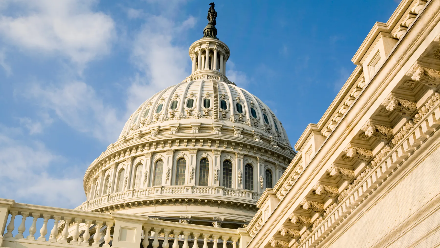 Close shot of the U.S. Capitol dome against the bright blue sky.