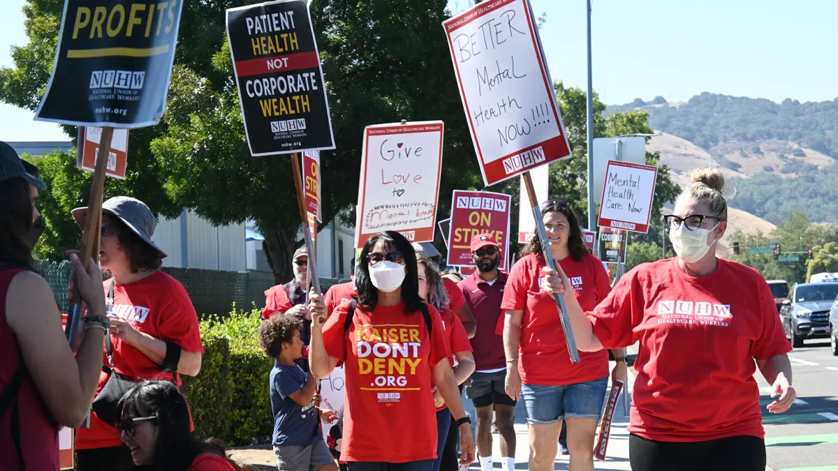Healthcare workers on strike hold a picket line outside a hospital.