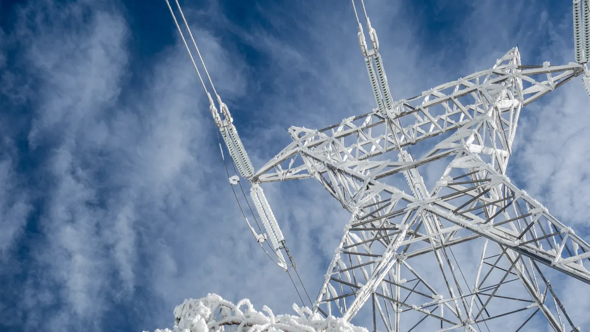 High voltage electric tower on a snowy day in the mountains.