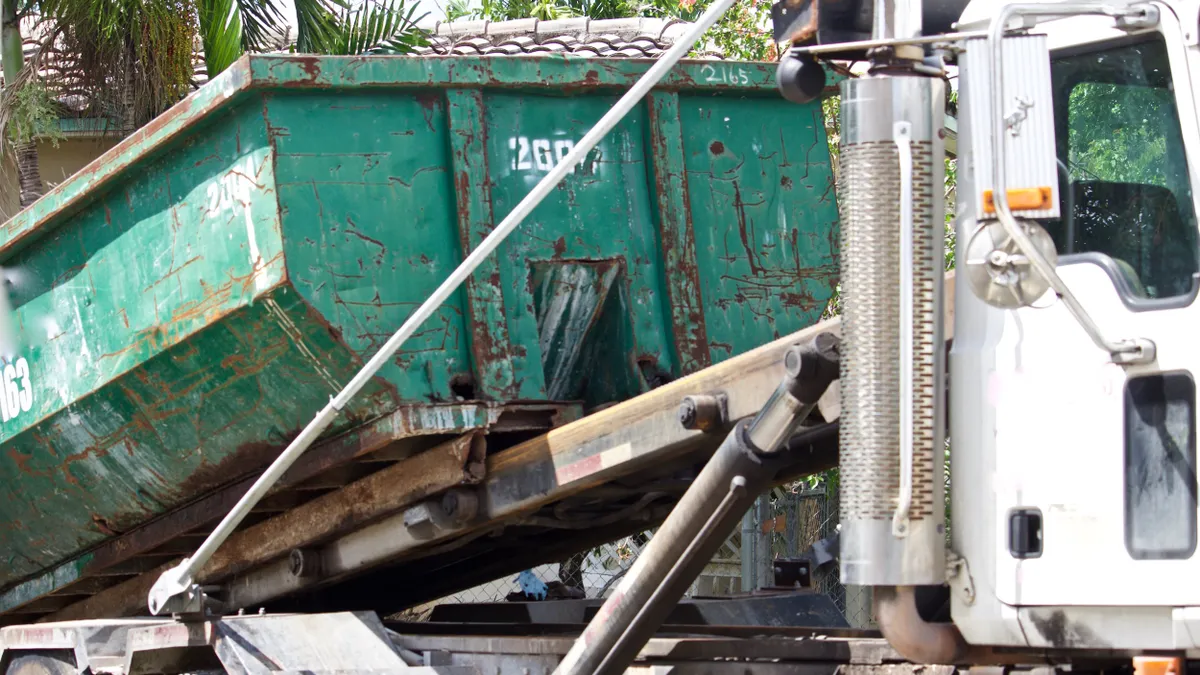 A white heavy duty truck with a roll-off container