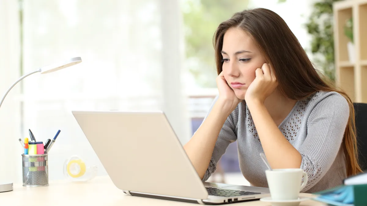 A glum woman looks at her computer