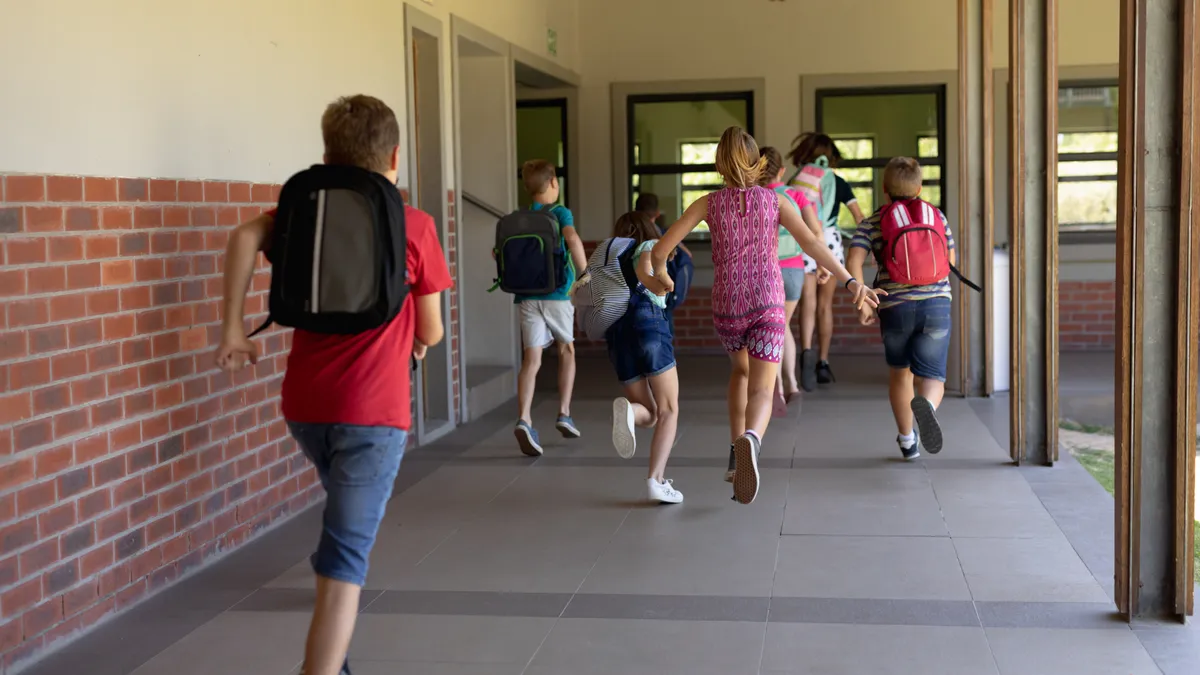 Group of schoolchildren running in an outdoor corridor at elementary school.