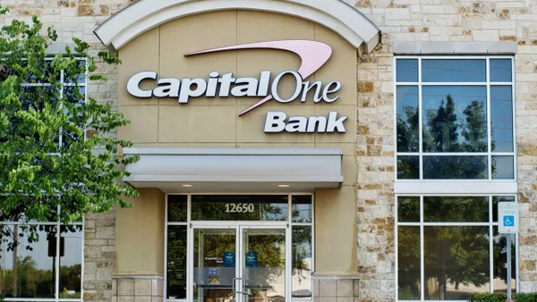 A brick commerical building entrance facade with a "Capitol One Bank" logo displayed above the doors. 