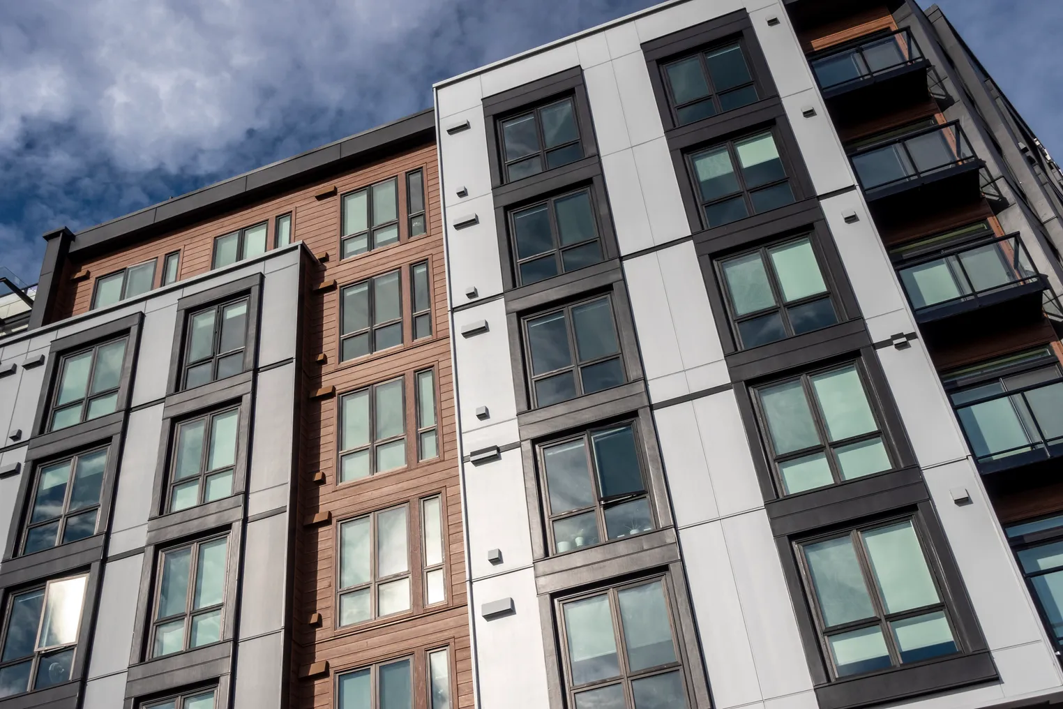 A modern, mid-rise apartment building with a wood and white panel facade.