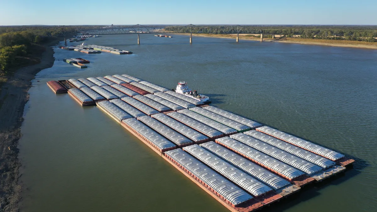 an aerial shot of the Ohio River shows barges tied together along the bank.