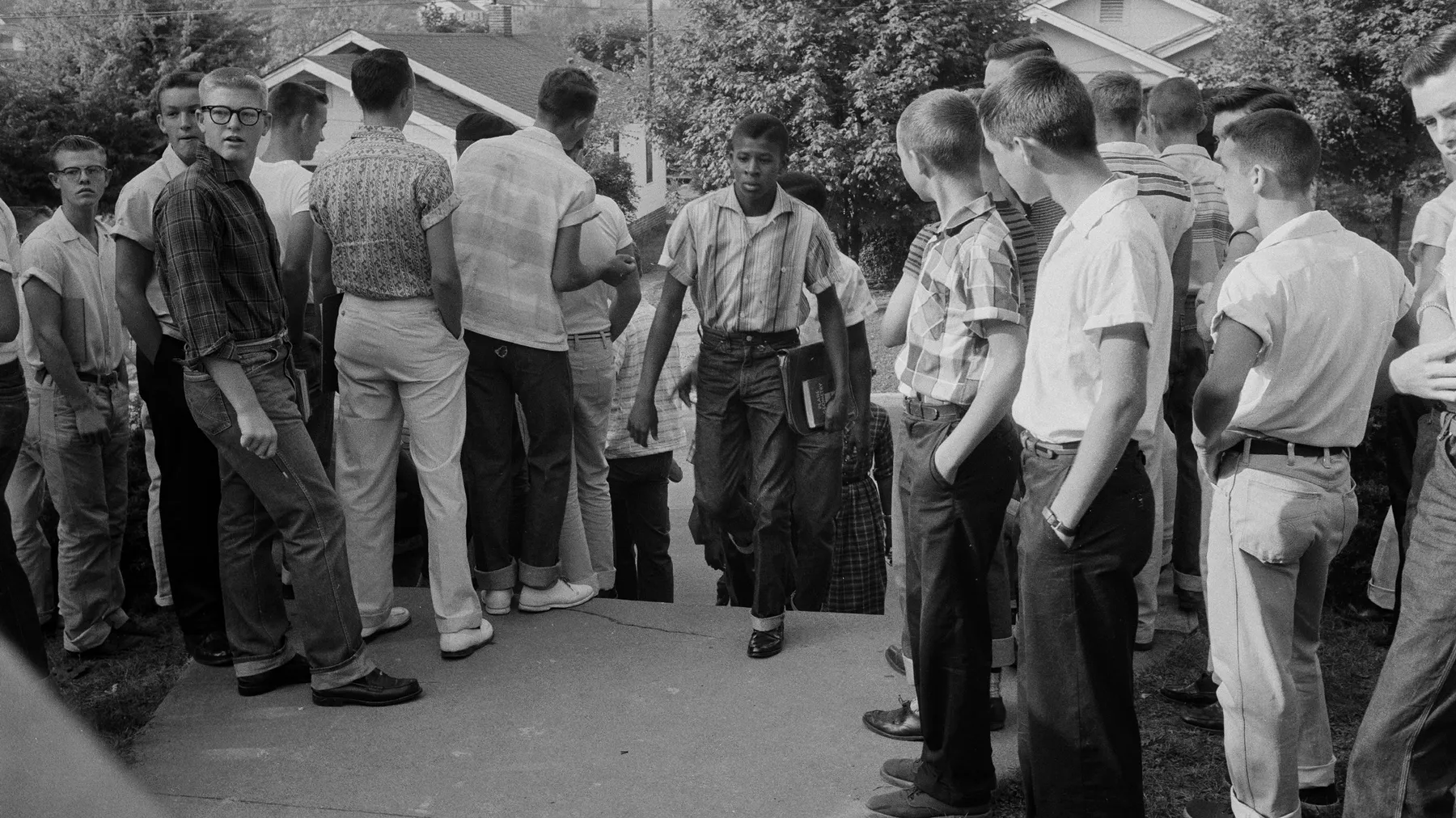 A line of Black students walk between a crowd of White segregationists on their way to Clinton High School