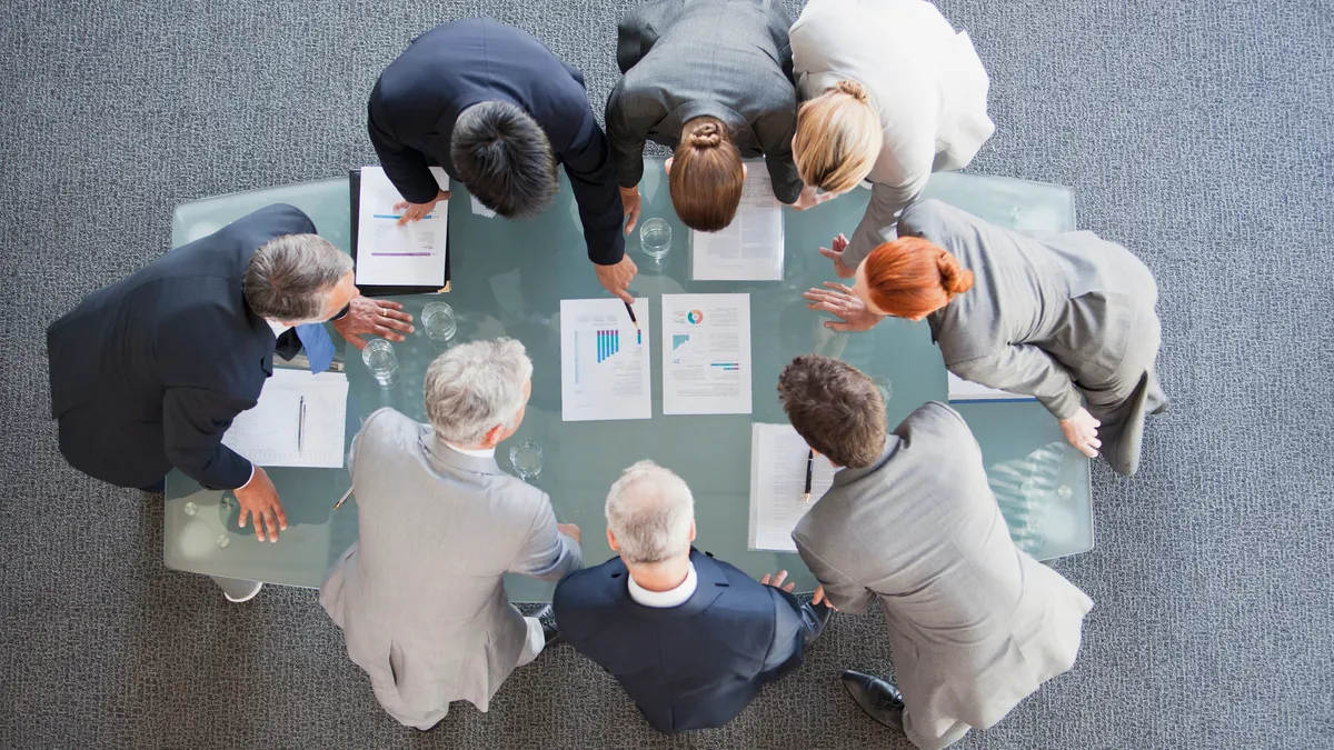 Business people huddled around paperwork on table