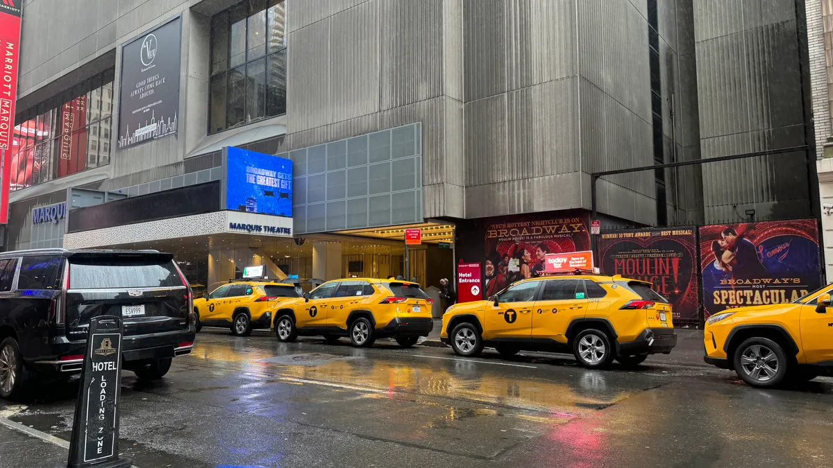 Taxis parked in front of a Manhattan hotel in the rain.
