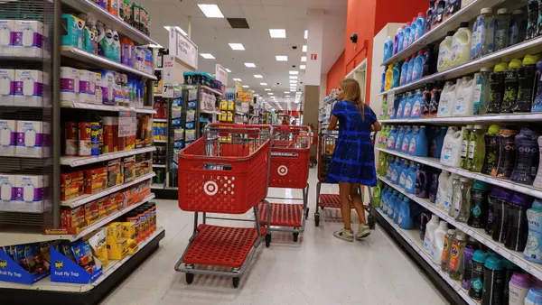 A person stands between shelves of items in a Target store with shopping carts