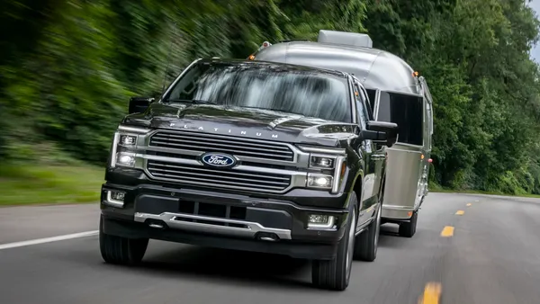 A 2024 F-150 Platinum driving on a road towing a trailer.