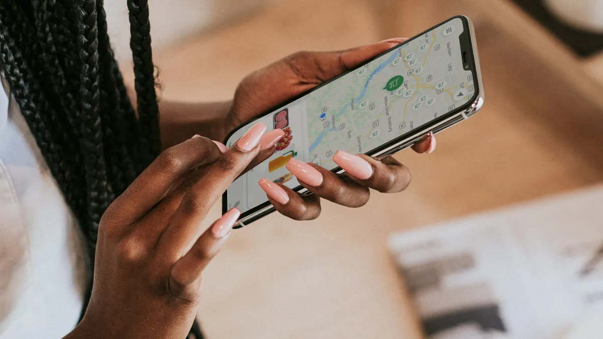 Close-up of hand holding phone with the screen showing food items below a map