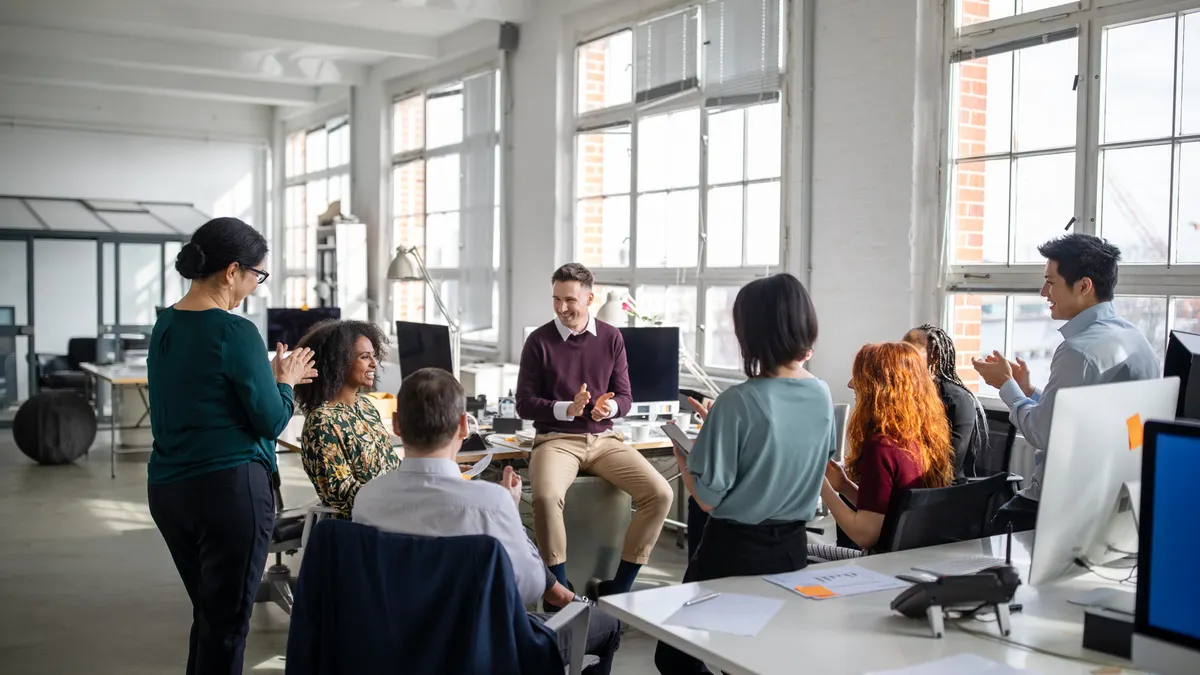Group of business people clapping hands for a coworker in staff meeting. Multi-ethnic business team applauding for a female colleague in a meeting.