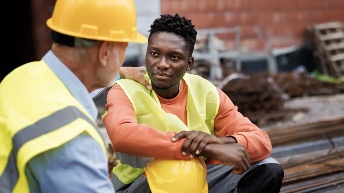 Senior man consoling his colleague at construction site.